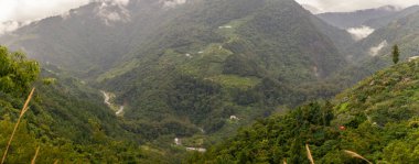 Dolaşan bir nehrin üzerinde yoğun bitki örtüsüyle kaplı yuvarlanan yeşil dağlar, dağınık kırsal evlerin ve ekili terasların üzerinde sürüklenen sis, sakin ve el değmemiş bir manzara yaratıyor. Tayvan, Asya 'da yakalandı..