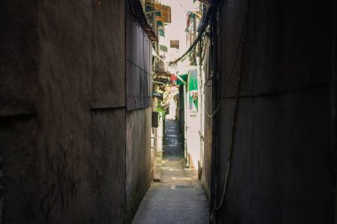 Açığa çıkmış elektrik kabloları ve güneş ışığıyla aydınlanan açık alana giden mimari unsurların yer aldığı eski dokulu duvarlarla çevrili dar bir sokak kentsel Taipei mahallesine bir göz atma imkanı sunuyor. Tayvan, Asya 'da yakalanmış..