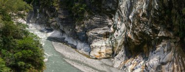 Turkuaz nehri derin vadide esiyor, yüzyıllar boyunca aşınmayla şekillenen pürüzsüz mermer kayalıkları oyuyor, yemyeşil bitki örtüsüyle çevrili, çarpıcı bir doğal kontrastlık yaratıyor. Taroko Milli Parkı, Tayvan, Asya 'da yakalandı.