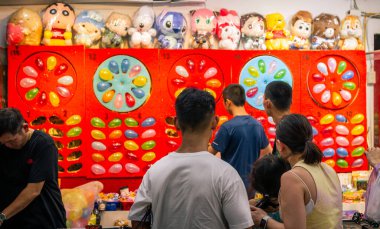 14-08-2023 - Taipei, Tayvan: Ziyaretçiler, parlak renkler, oyuncu dekorasyonlar ve enerjik festival atmosferinde doldurulmuş oyuncak ödülleri arasındaki ödülleri hedefleyen gece pazarında klasik balon patlatma oyunlarından hoşlanıyorlar. Tayvan, Asya 'da yakalanmış..