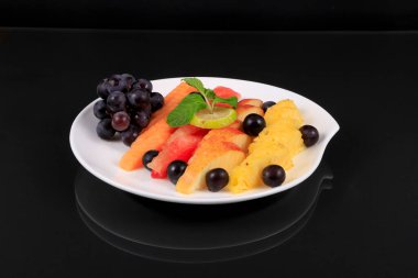 Siyah arka planda bir kase sağlıklı taze meyve salatası. sağlıklı yiyecekler