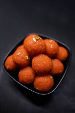 Geleneksel Hint tatlı Laddu 'sunun kapağı siyah bir kasede servis edilir.