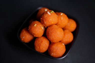 Geleneksel Hint tatlı Laddu 'sunun kapağı siyah bir kasede servis edilir.