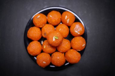 Geleneksel Hint tatlı Laddu 'sunun kapağı siyah bir kasede servis edilir.