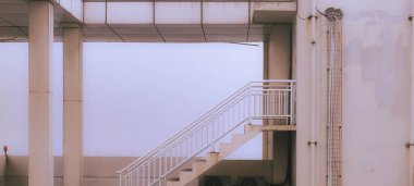 Açık Bej renkli beyaz parmaklıklı bir binanın dış merdiveni.