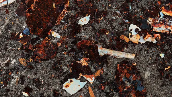 Gri Beton Yüzeydeki Paslı Metal Parçalar