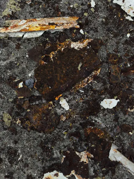 Gri Beton Yüzeydeki Paslı Metal Parçalar