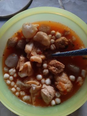 Bir kase sıcak ve lezzetli Endonezya köftesi çorbası. Çeşitli etler, börekler ve küçük toplar görülebilir..