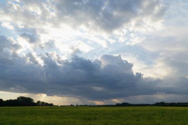 Şiddetli bir fırtınadan hemen önce Letonya kırsalının manzarası, dramatik bir gökyüzü ve yaklaşan bir fırtına gerginlik ve atmosfer hissi yaratıyor.