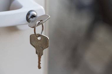 Bir kapının kilidine yerleştirilmiş, bulanık arkaplanı olan bir anahtarın yakın çekimi.