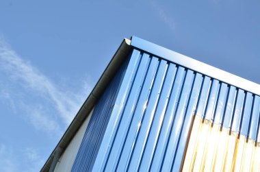 Mavi metal kaplamalı ve temiz gökyüzü olan modern bir endüstriyel binaya yakın çekim..