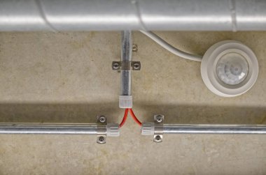 Tavana monte edilmiş hareket sensörü. Kanalda elektrik kabloları var..