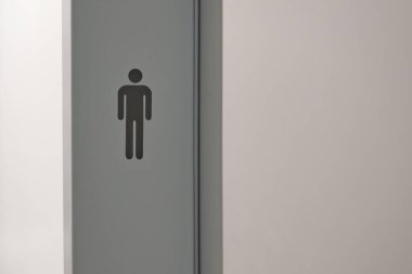 Gri duvarda erkek sembolü olan minimalist tuvalet tabelası..