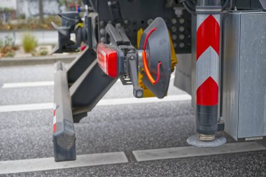 Işıklar ve uyarı işareti de dahil olmak üzere yansıtıcı güvenlik özellikleri gösteren bir kamyonun arka tarafının yakın çekimi. Görüntü, kamyonun park yerindeki tasarım ve güvenlik önlemlerini vurguluyor..