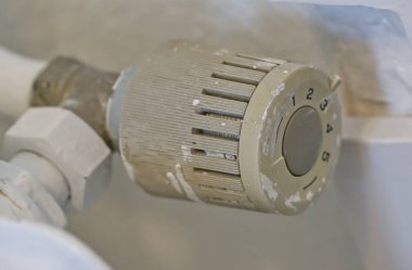 Isıtmalı radyatör valfinin yakın çekim görüntüsü. Valf biraz aşınmış ve boyanmış. Bu da bir evde ya da binada kullanıldığını gösteriyor..