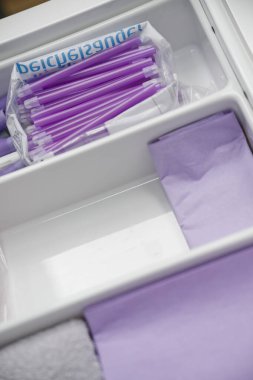 Mor kalemler ve mor kağıtlar içeren düzenli bir çekmece. Kalemler plastik bir torbada, kağıt ise düzgünce katlanmış, temiz ve düzenli bir çalışma alanı sergiliyor..