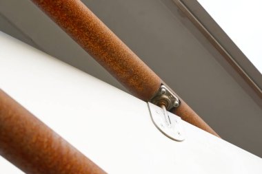 Beyaz bir yüzeye bağlı Flensburg limanındaki paslı metal parmaklıklar Phaenomenta dönüşümlü yapısına yakın çekim. Pas ve montajlanan donanımın dokusu ve detaylarını gösteriyor..
