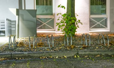 Düşen yapraklar ve çakıllarla çevrili metal dikenli bir arazinin gece manzarası. Yumuşak ışıklandırma sahneyi aydınlatıyor, çiviler ve doğal elementler arasındaki zıtlığı vurguluyor..