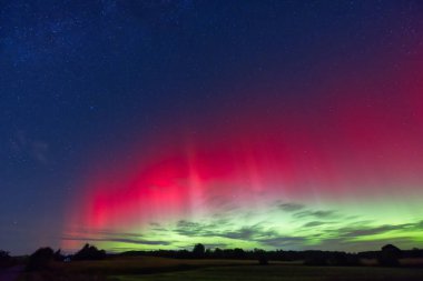 19 Eylül 2024 'ten, parlak kırmızı ve yeşil renklerle, Syd Danimarka' nın Kollund şehrinde gece gökyüzünü aydınlatan büyüleyici bir Aurora Borealis görüntüsü. Yıldızlar büyülü bir atmosfer için parıldıyor.