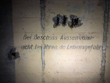 İkinci Dünya Savaşı sığınağının içine bakmak. Metin, yaşama tehlikesi nedeniyle dış duvarlara ateş edilmemesi konusunda uyarıyor. Duvar eski bir sığınak ya da askeri tesisin bir parçası..