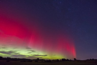 19 Eylül 2023 'ten parlak kırmızı ve yeşil renklerle gece gökyüzünü aydınlatan büyüleyici bir Aurora Borealis görüntüsü. Yıldızlar arka planda görünür, sakin bir manzara yaratırlar..
