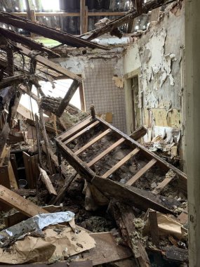 Çökmüş ahşap yataklı ve döküntüleri yere saçılmış harap bir oda. Duvarlarda ciddi hasar ve çürüme izleri var. Boya ve malzemeler soyulmuş..