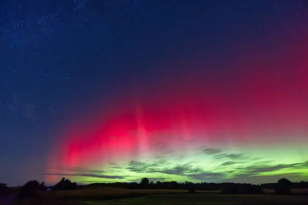 19 Eylül 2024 'ten, parlak kırmızı ve yeşil renklerle, Syd Danimarka' nın Kollund şehrinde gece gökyüzünü aydınlatan büyüleyici bir Aurora Borealis görüntüsü. Yıldızlar büyülü bir atmosfer için parıldıyor.
