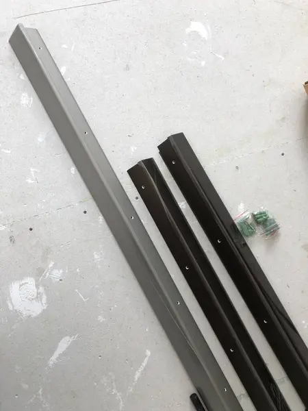 Açık renkli bir yüzeye, koyu yeşil ve gri de dahil olmak üzere çeşitli renklerde metal şeritler serilir. Yakınlarda küçük plastik bağlayıcılar görülebilir..