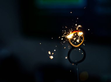 Biri parlak kıvılcımlarla kıvılcımlar saçan iki halkanın yakın çekimi, koyu bir arkaplana ayarlanmış. Görüntü, parlak metalle parlak kıvılcımlar arasındaki kontrastı yakalıyor..