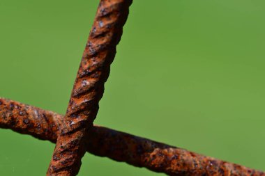 Paslı metal çubukların yakın plan görüntüsü bulanık yeşil arkaplan ile kesişiyor..