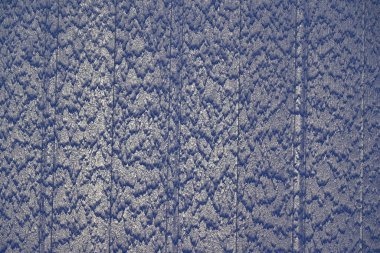 Bir şelale çizgili bir tasarımla mavi bir duvardan aşağı akar ve aşağı doğru akan eşsiz bir gerçek su deseni yaratır.