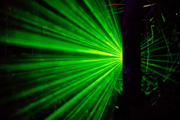 Merkezi bir noktadan yayılan canlı yeşil lazer ışınları dinamik ve enerjik bir atmosfer yaratıyor. Arka plan karanlık, lazerlerin parlaklığını arttırıyor..