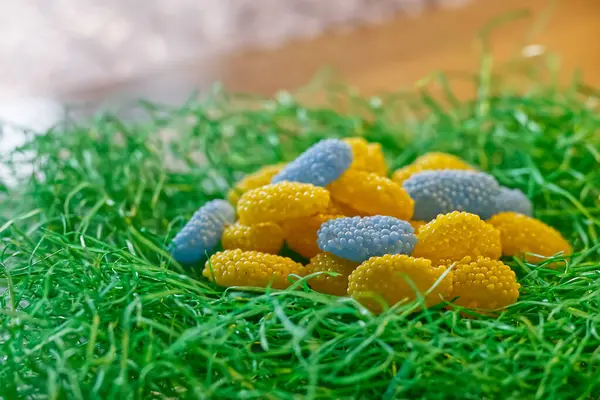 Paskalya yumurtaları ve Ukrayna bayrağı renginde paskalya şekerleri yeşil, çimen benzeri bir kumaş üzerinde. Yukarıdan gelen şekerler sarı ve mavidir ve incili yumurta olarak adlandırılır..