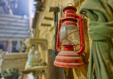 Kırsal bir atölyede tozlu bir kırmızı fener ahşap bir duvara asılır..