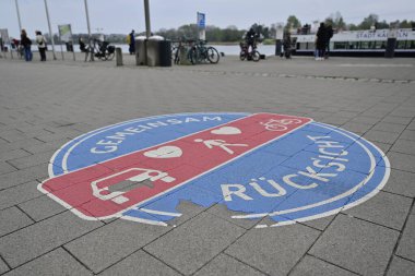 Kappeln 'de arabaların, yayaların ve bisikletlerin sembollerinin yer aldığı bir kaldırıma çizilmiş dairesel yol tabelası. İşaret, farklı yol kullanıcıları arasında paylaşılan alan ve karşılıklı saygıyı vurguluyor