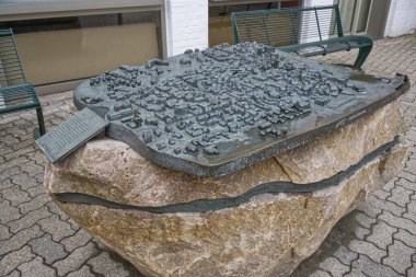 Kappeln 'de binalar, sokaklar ve yel değirmeninin yer aldığı tarihi bir kasaba planını gösteren bronz bir yardım haritası. Rahatlamanın dokusu ve derinliği mimari detayları vurguluyor..