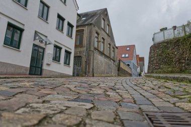Modern ve geleneksel mimarinin bir karışımının yer aldığı Kappeln City 'de tuhaf bir mahallede dolambaçlı bir kaldırım taşı caddesi. Gökyüzü bulutlu, sahneye karamsar bir atmosfer ekliyor..