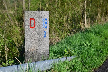 Krusa 'daki Alman Danimarka sınırında yol kenarı bir dönüm noktasıdır. Kırmızı ve mavi renklerle işaretlenmiştir. Arka planda yeşil çimenler ve ağaçlar vardır..
