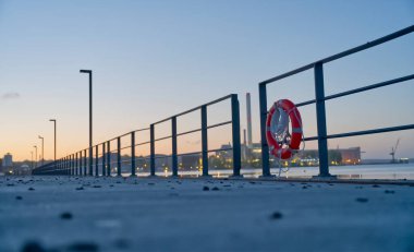Flensburg Fjord 'daki Nordertorkai ve Galwikpark arasındaki gezintinin bitiminden sonra ön planda martı dışkılarıyla kaplı bir can simidiyle Flensburg rıhtımının manzarası