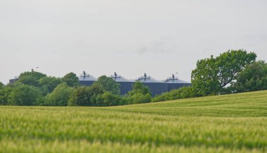 Danimarka 'nın Kvaers kentindeki biyogaz sahasının BIO-Gaz deposuna uzak görüş alanı ayrıca büyük siyah varil şekilli depolama alanı