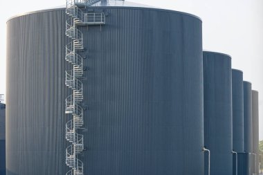 Danimarka 'nın Kvaers kentindeki biyogaz sahasının BIO-Benzin deposunun tam görüntüsü ayrıca büyük siyah fıçı şeklinde bir depo, ön tarafında uzun ve yüksek döner bir merdiven var.