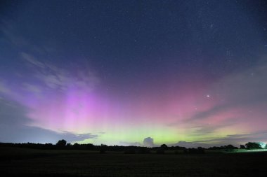 Bulutları ve yeşil, turkuaz, kırmızı, pembe, mavi ve sarı renkteki aurora bir resimde Danimarka, Kollund 'daki Alman sınırında çekildi.