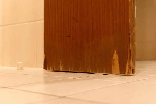 Büyük su hasarı banyodaki ahşap bir kapıda nem hasarı var. Duş alma, yıkama, yüksek nem ve su damlaları neden olmuş.