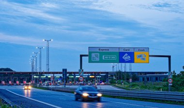 Danimarka 'da Korsor yakınlarındaki Öresund Oeresund Köprüsü' ndeki gişe bariyerleri. Alacakaranlıkta araba ve trafik ışıklarıyla Büyük Kemer 'i geçiyor.