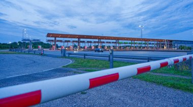 Danimarka 'nın Korsor Kursoer kentinin doğu yakasındaki Öresund Oeresund Köprüsü' ndeki gişe bariyerlerinin önünde alacakaranlıkta kırmızı ve beyaz bir bariyer bulunuyor.