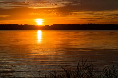Gezinti güvertesinde ve tatil köyü Gluecksburg 'un plajında, 23 Temmuz 2025' te şiddetli fırtınalardan sonra gün batımı özellikle ön plandaki çimlerle renklidir.