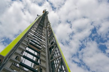 Flensburg İtfaiye Teşkilatı 'nın kurtarma merdivenleri hafif bulutların altında ve Flensburg fiyordunda mavi gökyüzünün altında göğe doğru yükseliyor.