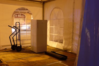 Ahşap döşemeli loş bir çadırın içinde bir buzdolabı ve bebek..