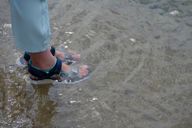 Flensburg Limanı 'ndaki sahilde sığ sularda sandalet giyen bir çocuk..