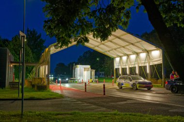 Akşamları Padborg 'da Danimarka ile Almanya arasındaki sınır kapısı ve gece vakti aydınlanmış sınır kontrol noktası için beyaz tepe örtüsü polis teftişi